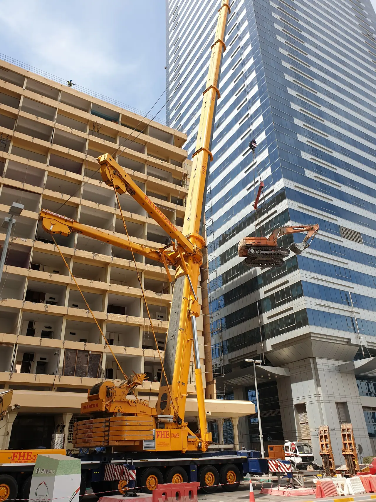FHE crane lifting an excavator up the face of a building