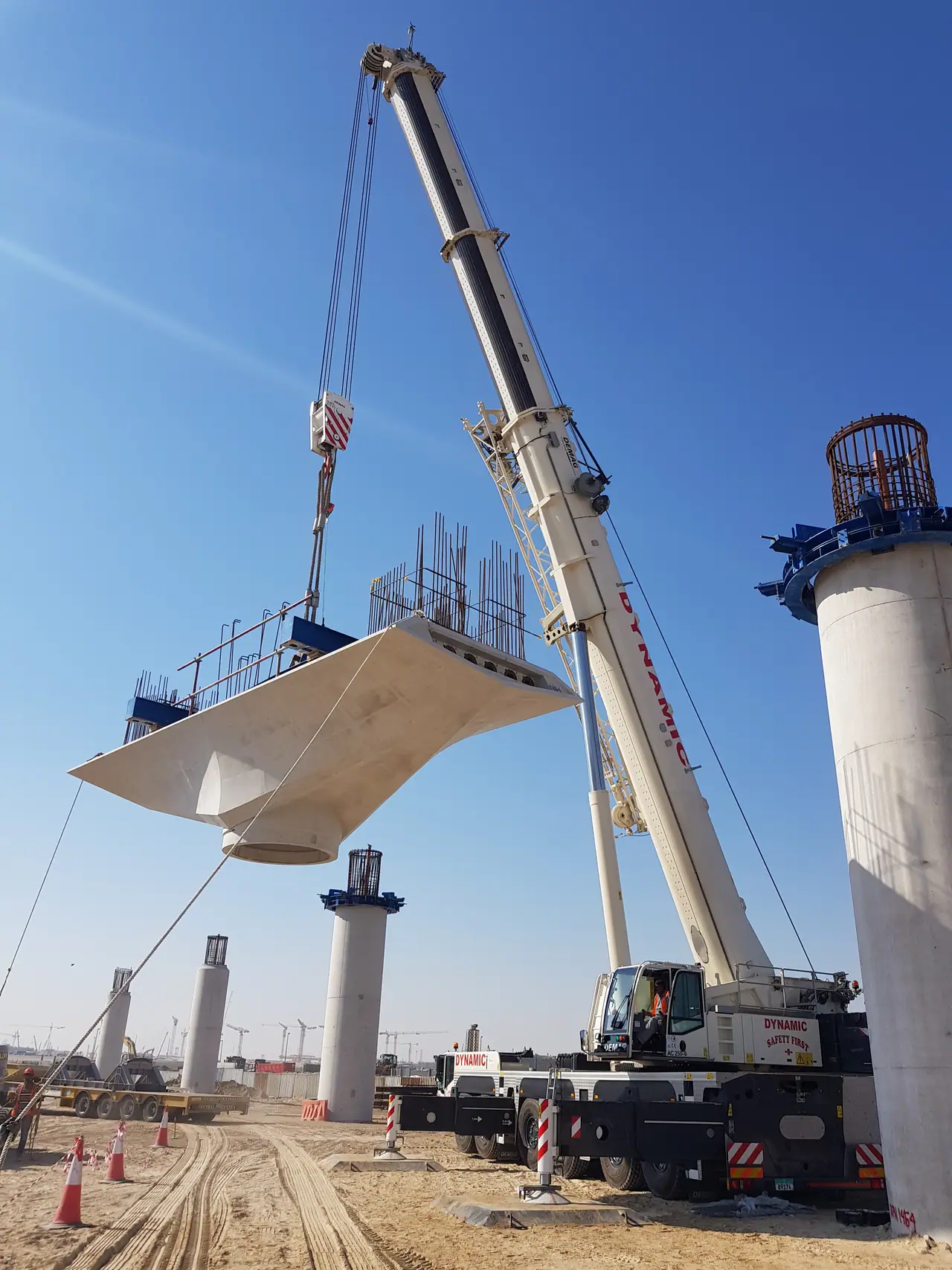 White mobile crane lowering a precast concrete pier cap onto a bridge column