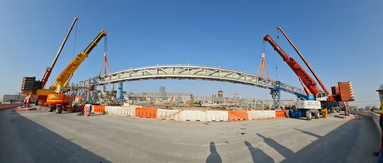 Two cranes performing a tandem lift of a steel pedestrian bridge
