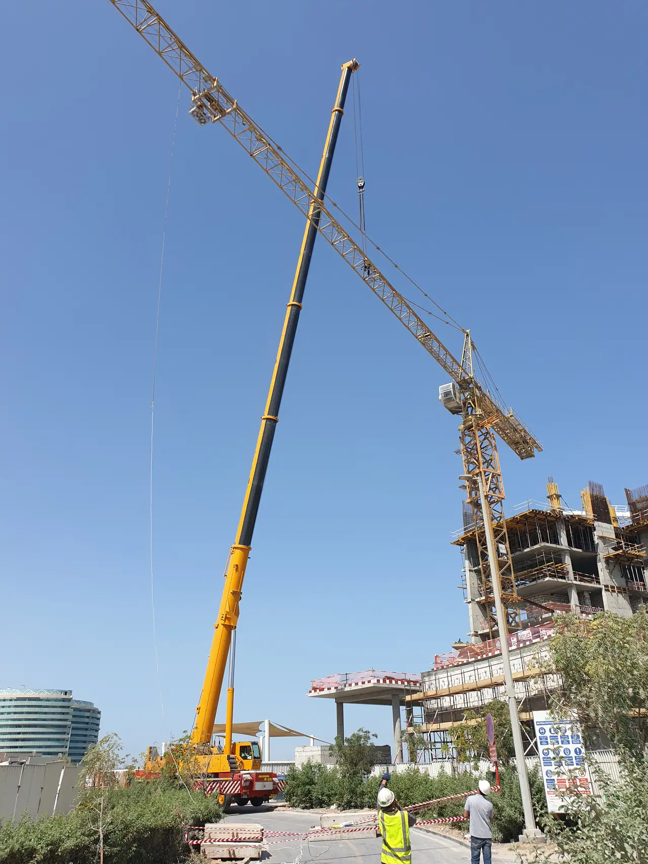 Telescopic mobile crane dismantling a tower crane on a city site